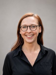 Lächelnde Person mit Brille in schwarzem Shirt, Porträtfoto.
