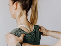 Junge Frau wird von Händen von hinten an den Schultern angefasst