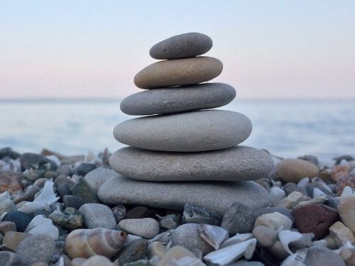 Steinpyramide aus flachen Steinen auf einem Strand im Hintergrund das Meer und Horizont